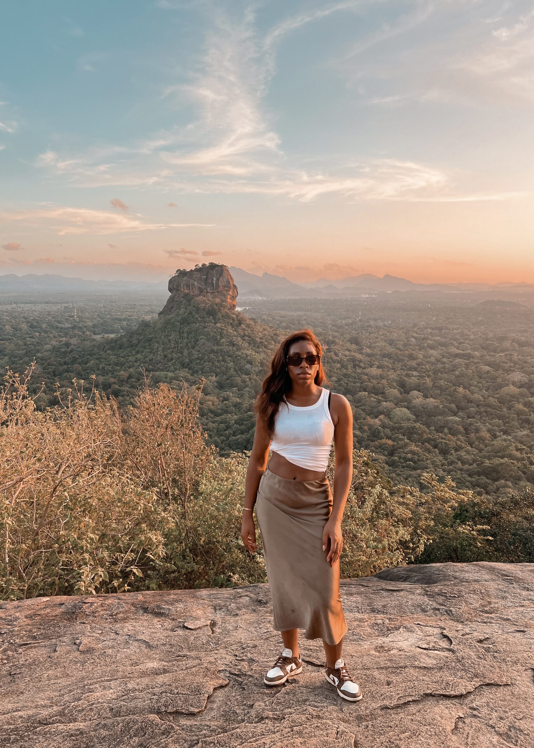 Vrouw poseert voor de Lion's Rock in Sri Lanka